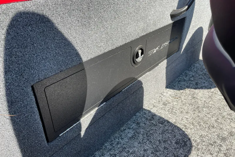 Slide: The Image of 2026 Tracker Targa V-18 Combo interior storage compartment with lock, carpeted finish. - 27