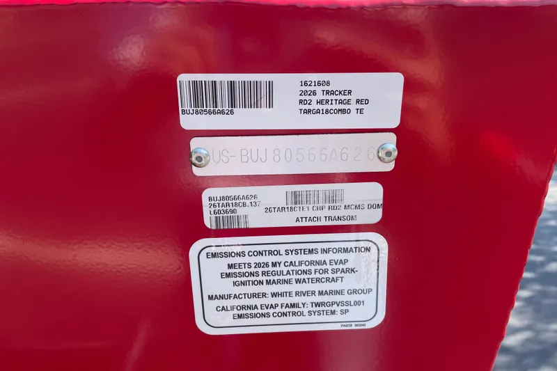 Slide: The Image of 2026 Tracker Targa V-18 Combo boat identification and emissions labels on red surface. - 105