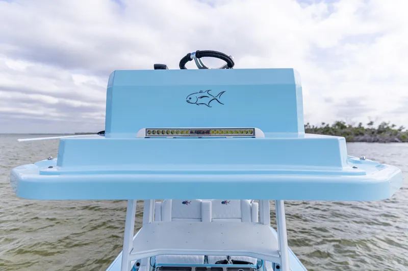 Slide: The Image of 2026 Crevalle 26 HCO boat console with fish logo, on calm water under cloudy sky. - 12