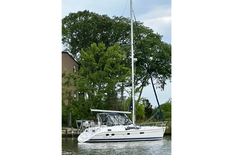 The Image of 2002 Hunter Passage 420 sailboat docked by lush green trees. - 0