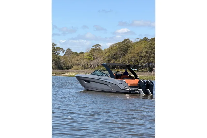 Slide: The Image of 2021 Cruisers Yachts 338 Bow Rider on a serene lake with trees in the background. - 3