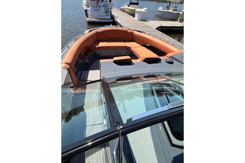 Slide: The Image of 2021 Cruisers Yachts 338 Bow Rider with orange seating, docked by the water. - 9