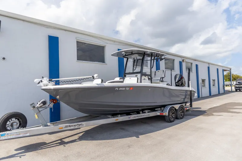Slide: The Image of 2023 Crevalle 26 HCO boat on trailer, parked outside a building under a cloudy sky. - 14