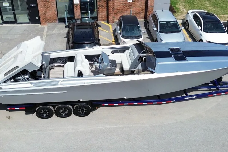 Slide: The Image of A 2017 Monte Carlo 420 boat on a trailer, parked near several cars. - 3