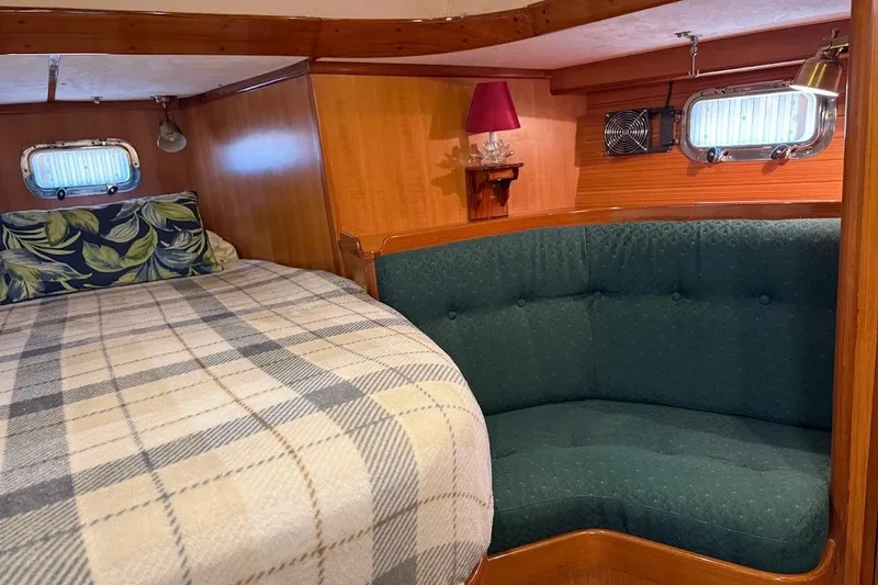 Slide: The Image of Cozy 1997 Taswell 50 yacht cabin with bed, green sofa, and portholes. - 14