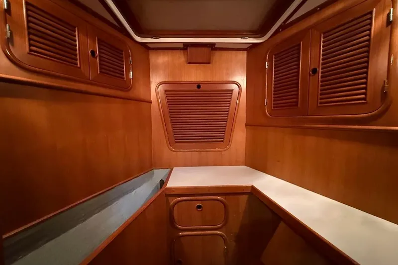 Slide: The Image of Interior of 1997 Taswell 50 yacht with wooden cabinetry and white countertop. Possible Workshop or office. - 25