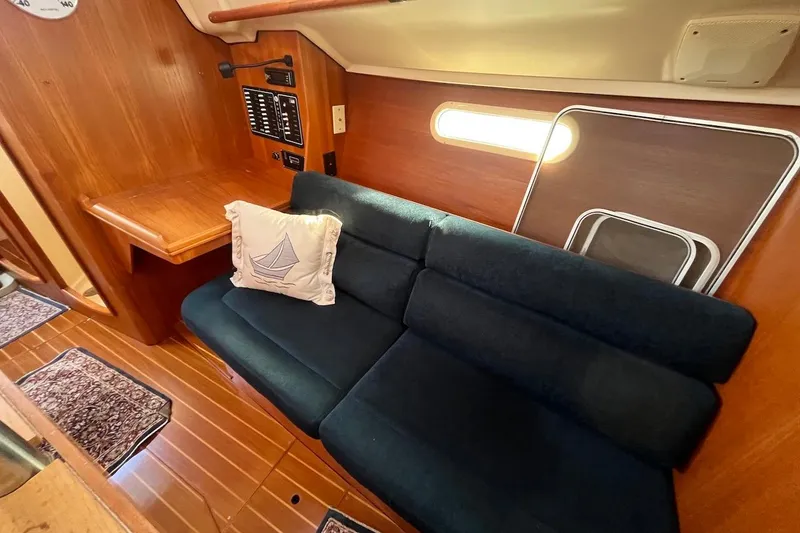Slide: The Image of Cozy interior of 2002 Hunter 326 sailboat with blue sofa and wooden accents. - 11