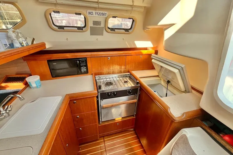 Slide: The Image of Compact kitchen in a 2002 Hunter 326 sailboat with stove, microwave, and sink. - 12