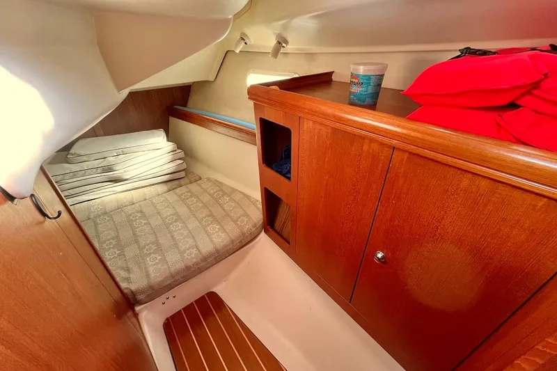 Slide: The Image of Cozy cabin interior of 2002 Hunter 326 sailboat with wooden cabinetry and cushioned seating. - 18