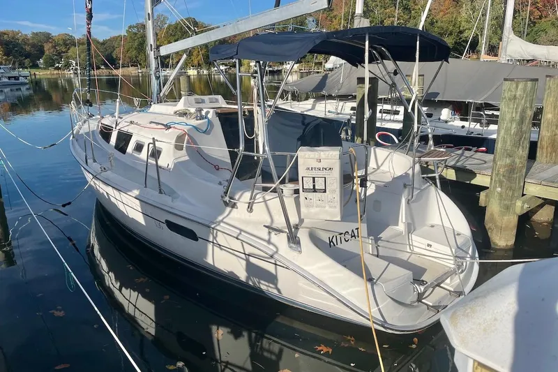Slide: The Image of 2002 Hunter 326 sailboat docked in a marina, featuring a sleek white design. - 2