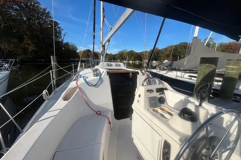 Slide: The Image of 2002 Hunter 326 sailboat cockpit with steering wheel, docked in a serene marina setting. - 3