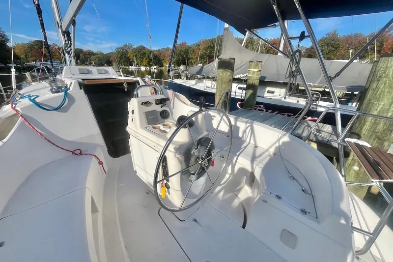 Slide: The Image of 2002 Hunter 326 sailboat cockpit with steering wheel, docked at marina under clear blue sky. - 4