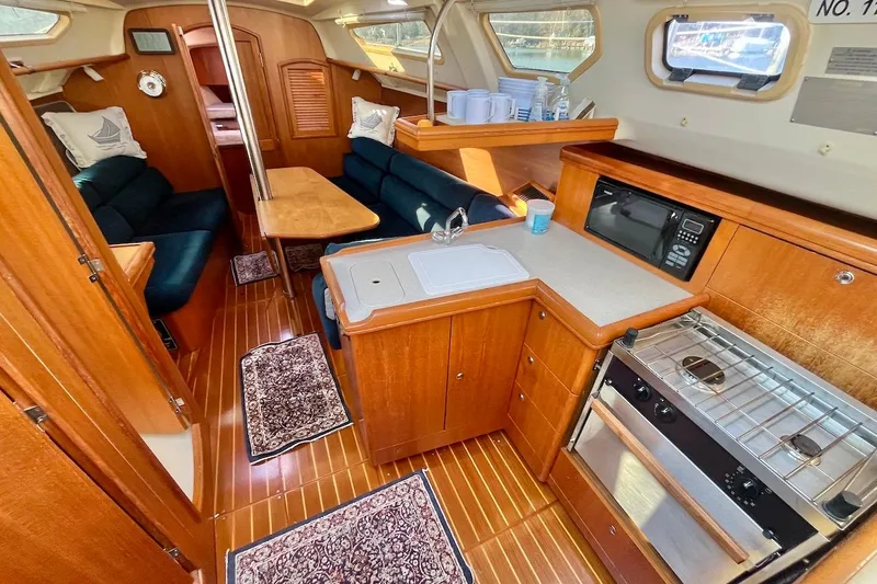 Slide: The Image of Interior of a 2002 Hunter 326 sailboat with wood finish and compact kitchen. - 7
