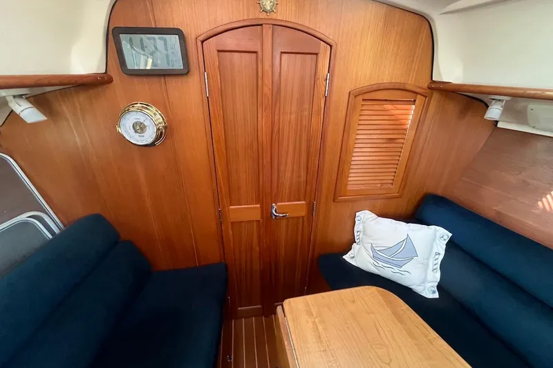 Slide: The Image of Interior of 2002 Hunter 326 sailboat with wooden paneling and navy seating. - 9