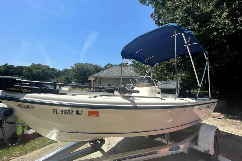 The Image of 2006 Key West 152 Center Console boat with blue canopy on trailer, sunny day. - 1