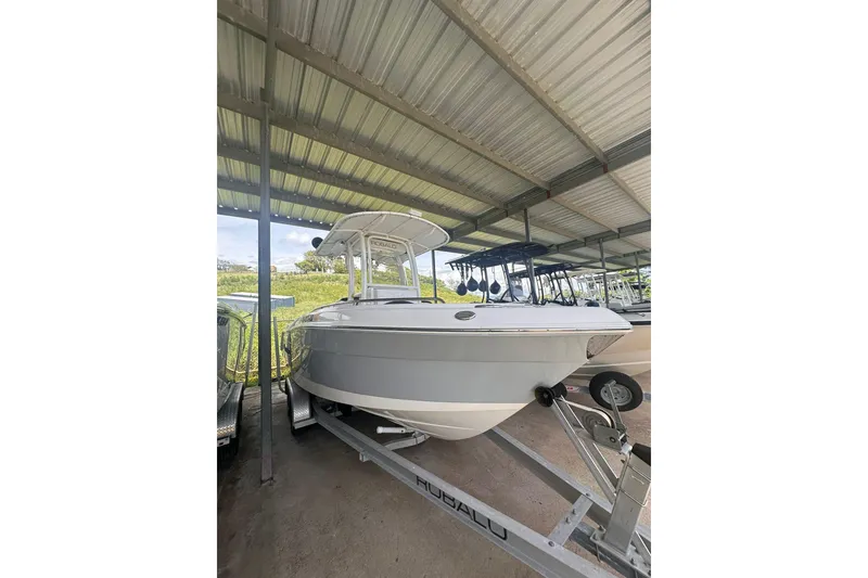 The Image of 2023 Robalo R222 Explorer boat on trailer under metal roof. - 1