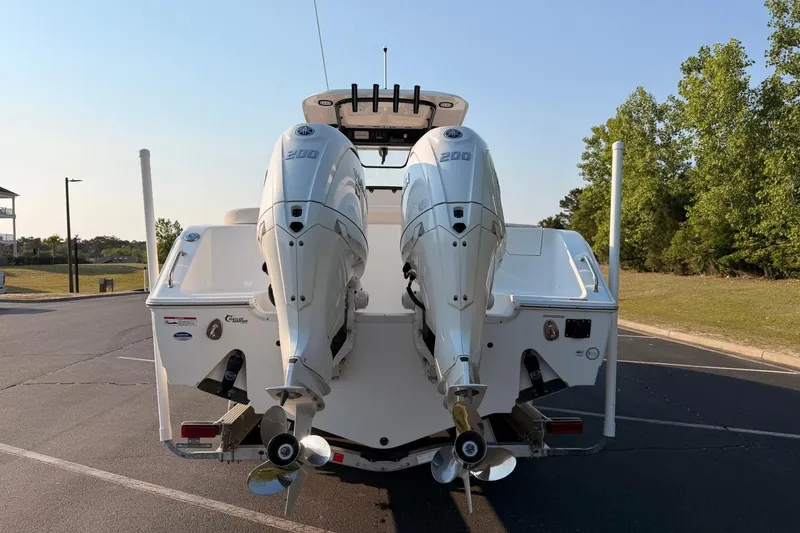 Slide: The Image of 2024 Sea Hunt Ultra 275 SE boat with dual outboard engines, parked outdoors. - 10