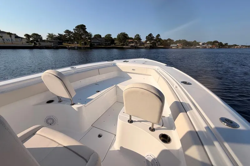 Slide: The Image of 2024 Sea Hunt Ultra 275 SE boat interior with seating, on a calm lake. - 16