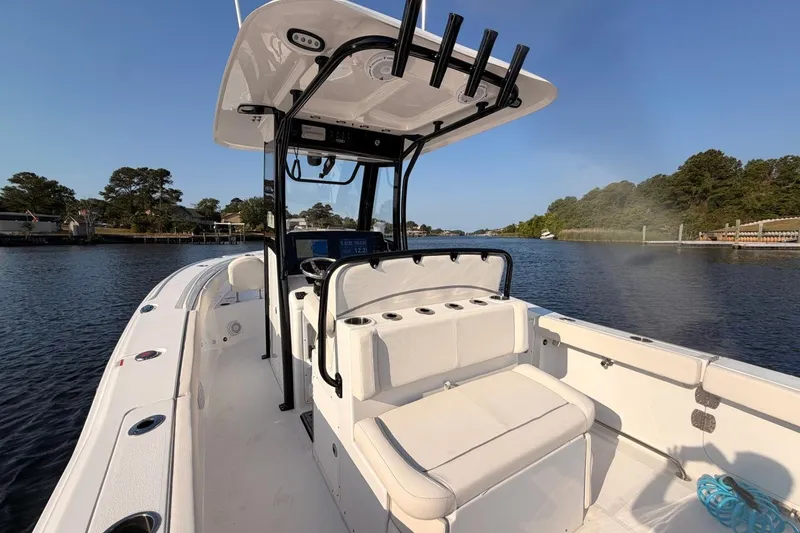 Slide: The Image of 2024 Sea Hunt Ultra 275 SE boat on calm water, showcasing sleek design and spacious seating. - 18