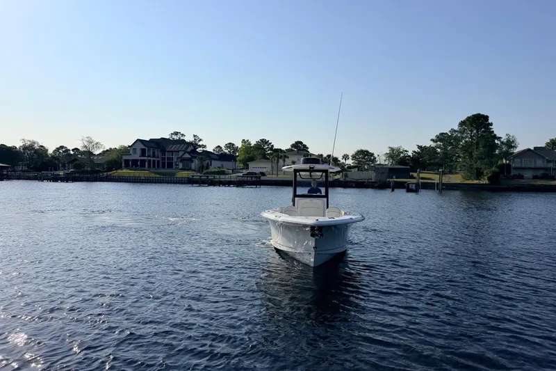 Slide: The Image of 2024 Sea Hunt Ultra 275 SE boat cruising on a calm lake near waterfront homes. - 21
