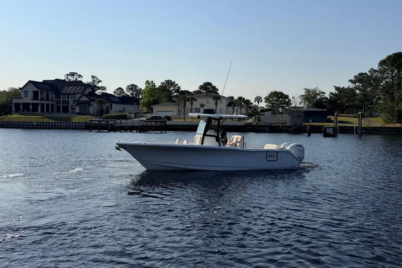 Slide: The Image of 2024 Sea Hunt Ultra 275 SE boat cruising on a calm lake near waterfront homes. - 22