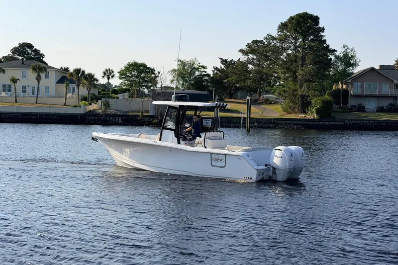 Slide: The Image of 2024 Sea Hunt Ultra 275 SE boat cruising on a calm waterway near residential area. - 23