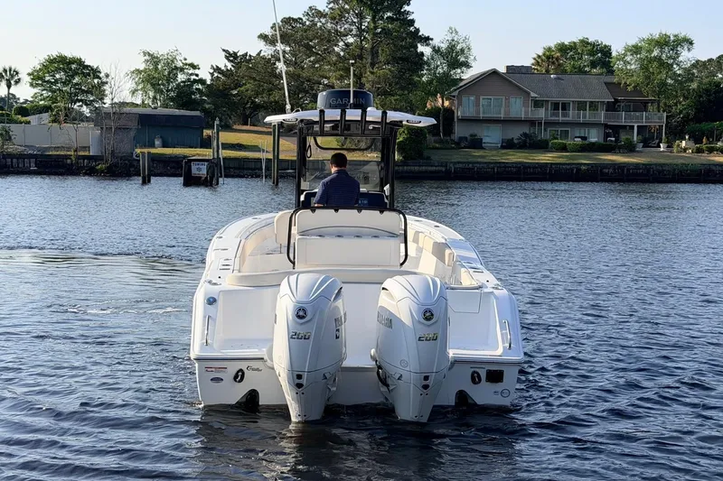 Slide: The Image of 2024 Sea Hunt Ultra 275 SE boat on calm water, rear view with dual engines. - 3