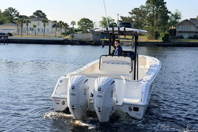 Slide: The Image of 2024 Sea Hunt Ultra 275 SE boat with dual Yamaha engines on a calm waterway. - 4