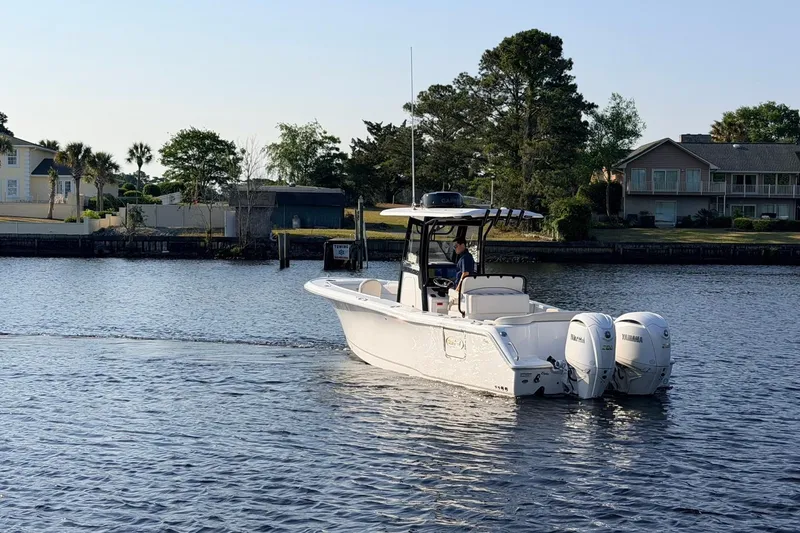 Slide: The Image of 2024 Sea Hunt Ultra 275 SE boat cruising on a calm waterway near residential area. - 5