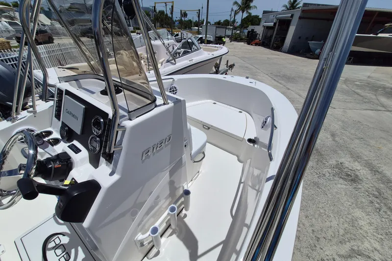 Slide: The Image of 2026 Robalo R180 Center Console boat with Garmin navigation system, docked outdoors. - 13