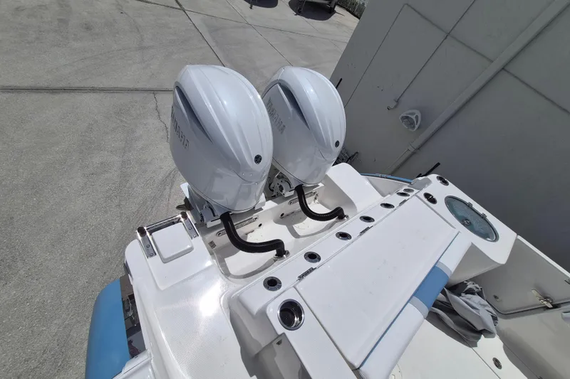 Slide: The Image of 2026 Robalo R250 Center Console boat with dual outboard engines, docked on concrete. - 17