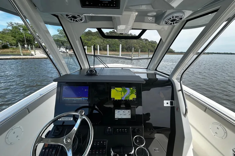 Slide: The Image of Cockpit view of 2023 Pursuit S 328 Sport boat with navigation screens and steering wheel. - 11