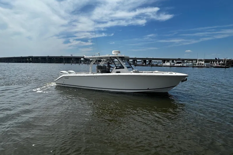 Slide: The Image of 2023 Pursuit S 328 Sport boat cruising on a sunny day near a marina. - 2