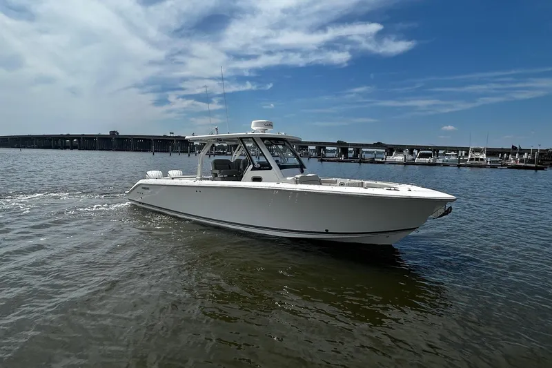 Slide: The Image of 2023 Pursuit S 328 Sport boat cruising on a sunny day near a marina. - 3