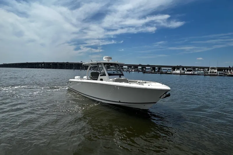 Slide: The Image of 2023 Pursuit S 328 Sport boat cruising on a sunny day near a marina. - 5