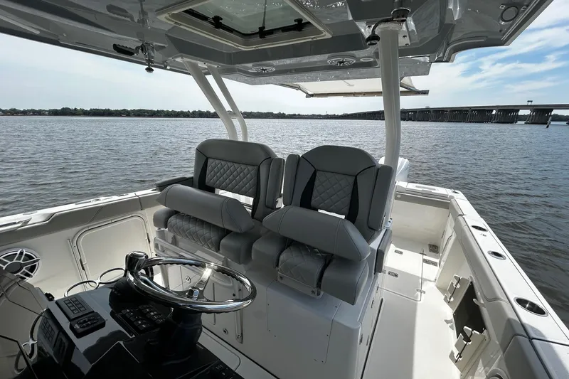 Slide: The Image of 2023 Pursuit S 328 Sport boat interior with dual seats and steering wheel on open water. - 7