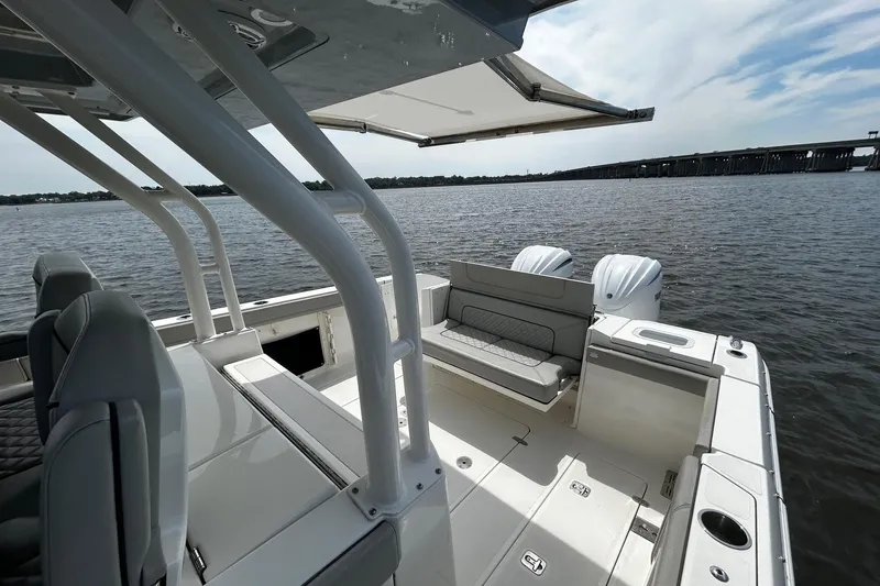 Slide: The Image of 2023 Pursuit S 328 Sport boat interior with seating, on calm water near a bridge. - 9
