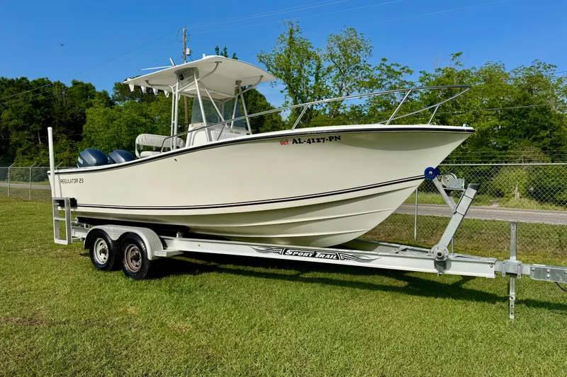 The Image of 1994 Regulator 23 Center Console boat on trailer, parked on grass. - 1