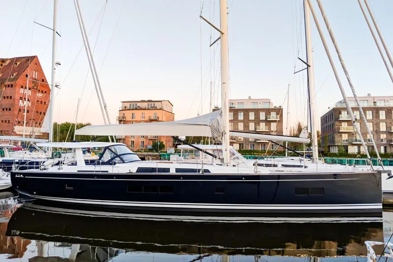 The Image of 2018 Hanse 675 yacht docked in a marina, with modern buildings in the background. - 0
