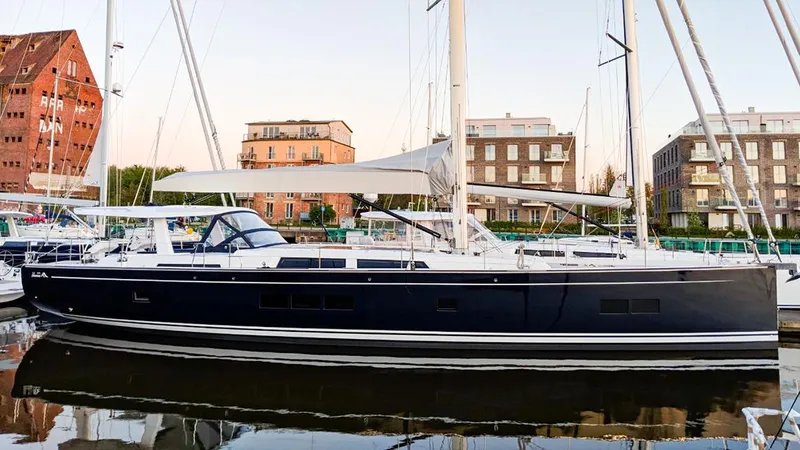 Slide: The Image of 2018 Hanse 675 yacht docked in a marina, surrounded by modern buildings. - 17