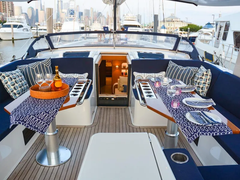 Slide: The Image of Luxurious 2018 Hanse 675 yacht deck with elegant dining setup and city skyline view. - 3