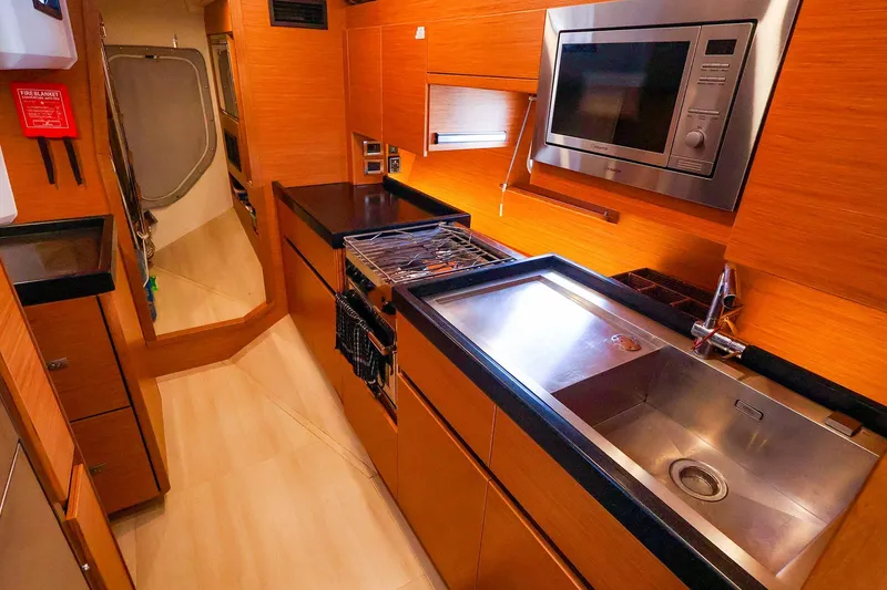 Slide: The Image of Luxurious 2018 Hanse 675 yacht kitchen with modern appliances and sleek wooden cabinetry. - 57