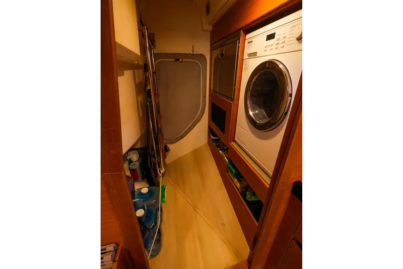 Slide: The Image of Laundry area inside 2018 Hanse 675 yacht with washing machine and storage shelves. - 64