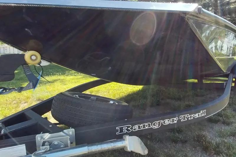 Slide: The Image of 2023 Ranger RT198P boat on trailer, sunlit, grassy background. - 13