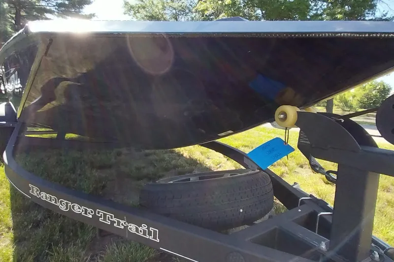 Slide: The Image of 2023 Ranger RT198P boat trailer with spare tire, parked on grass. - 14