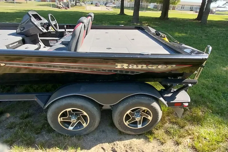 Slide: The Image of 2023 Ranger RT198P boat on trailer, parked on grass, showcasing sleek design and dual seats. - 2