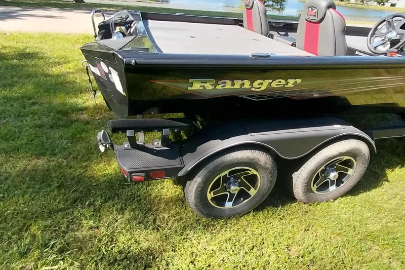 Slide: The Image of 2023 Ranger RT198P boat on trailer, parked on grass near a lake. - 23