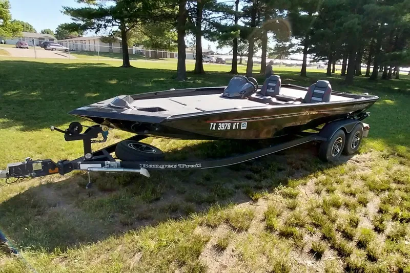 Slide: The Image of 2023 Ranger RT198P boat on trailer, parked on grassy area near trees. - 27