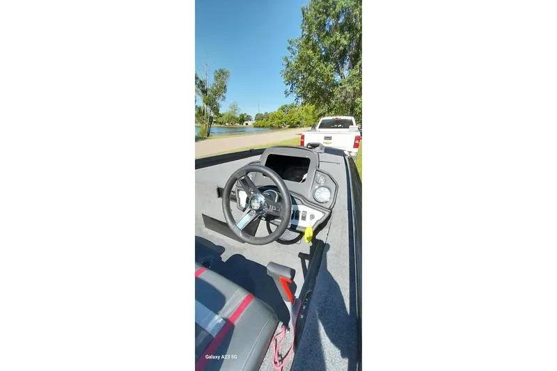 Slide: The Image of 2023 Ranger RT198P boat interior with steering wheel, parked near a lake. - 8