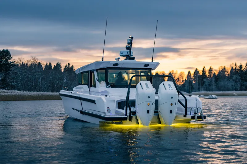 Slide: The Image of 2026 Axopar 38 Cross Cabin boat on water at sunset with illuminated engines. - 14